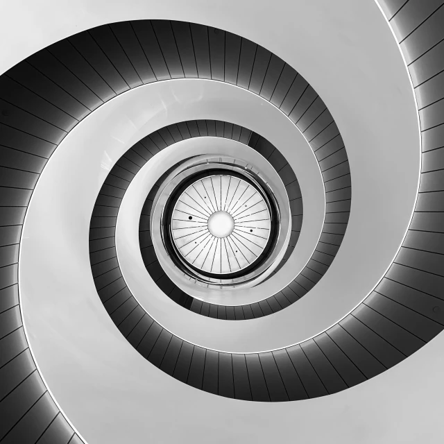 a spiral staircase made of grey materials on a gray background