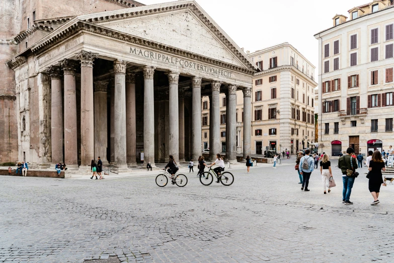 people standing around and walking in front of some very large buildings