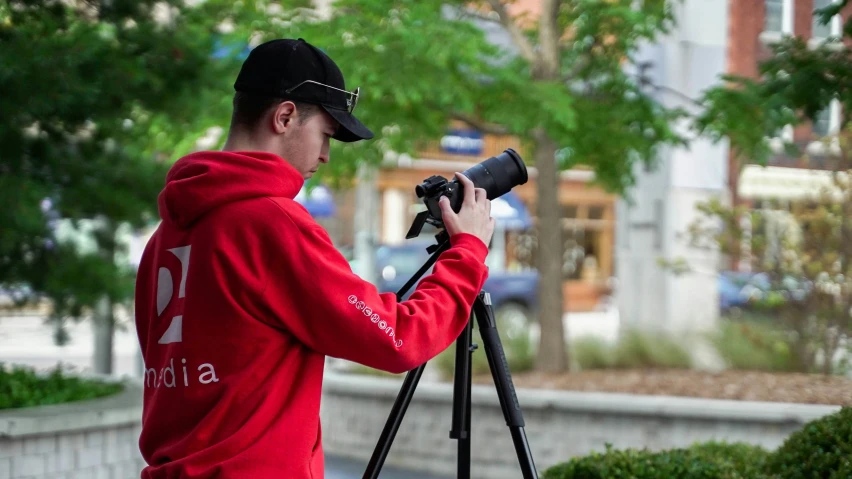 a man in a red shirt is holding a camera