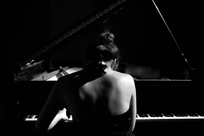 a woman sits and stares at the piano