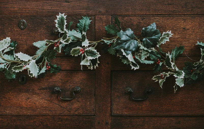 holly garland and holly leaves on a wooden cabinet