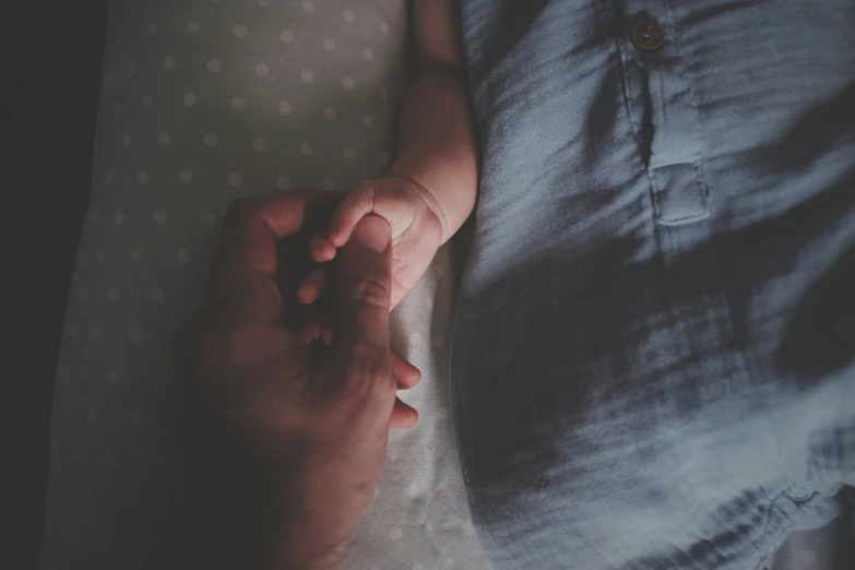 baby being held by someones hands while laying on the couch