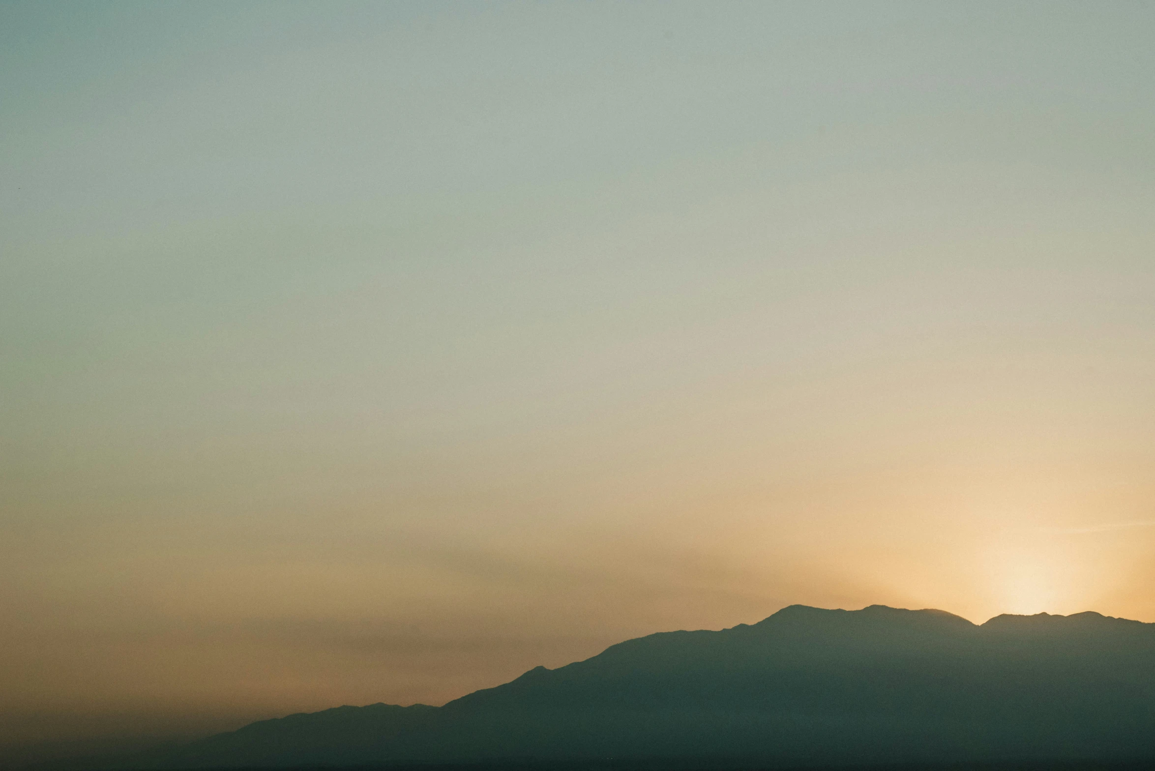 the sun is shining over some mountains on a clear day