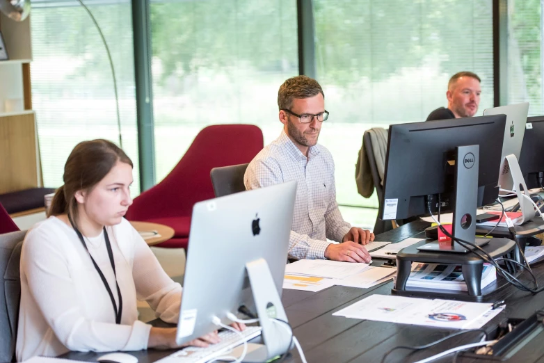 a group of people are in a large room working on computers