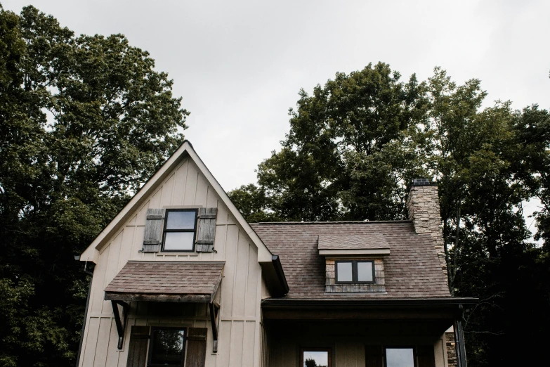 a white house with a brown roof and a tree