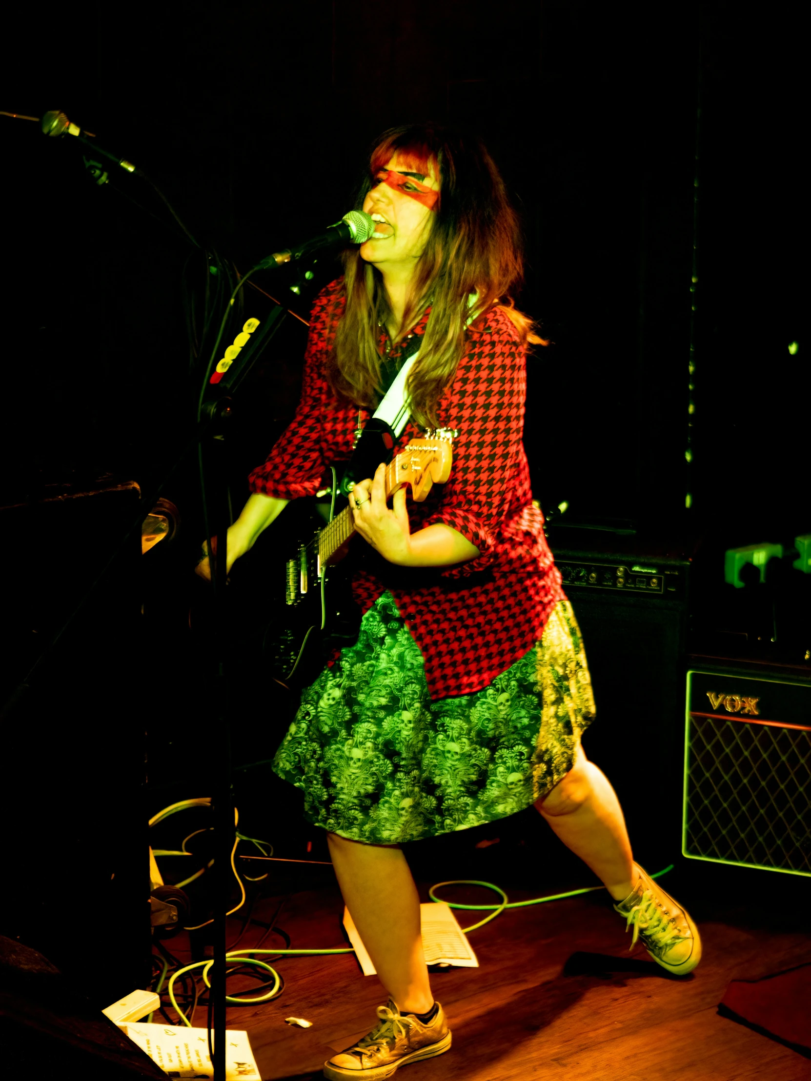 woman in red and green dress with green skirt playing guitar