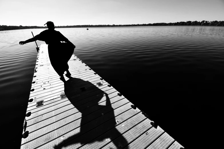 a woman wearing a hat walking along a pier