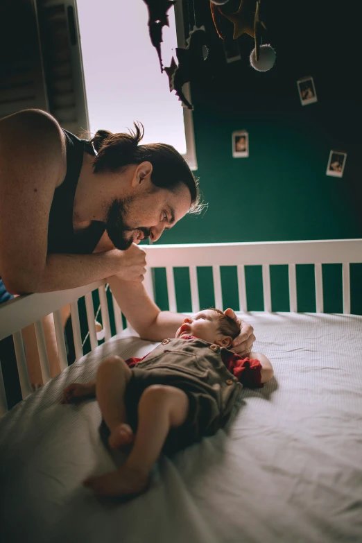 the child is on top of his mother while she lays in bed