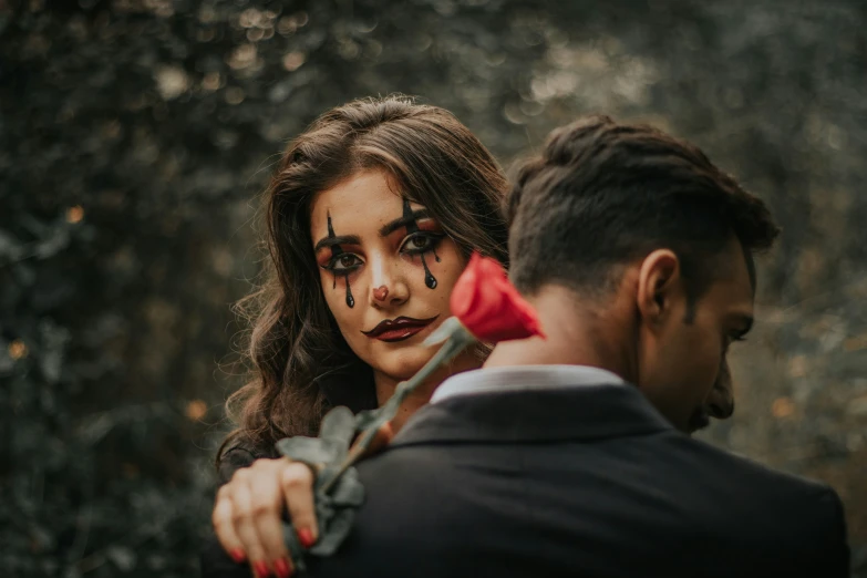 a young man and a woman with black makeup holding scissors