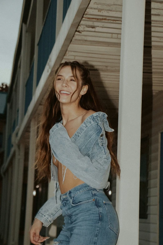 a woman posing near a building wearing jeans