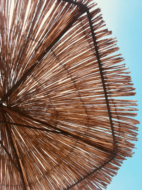 closeup of a straw sun umbrella in the blue sky