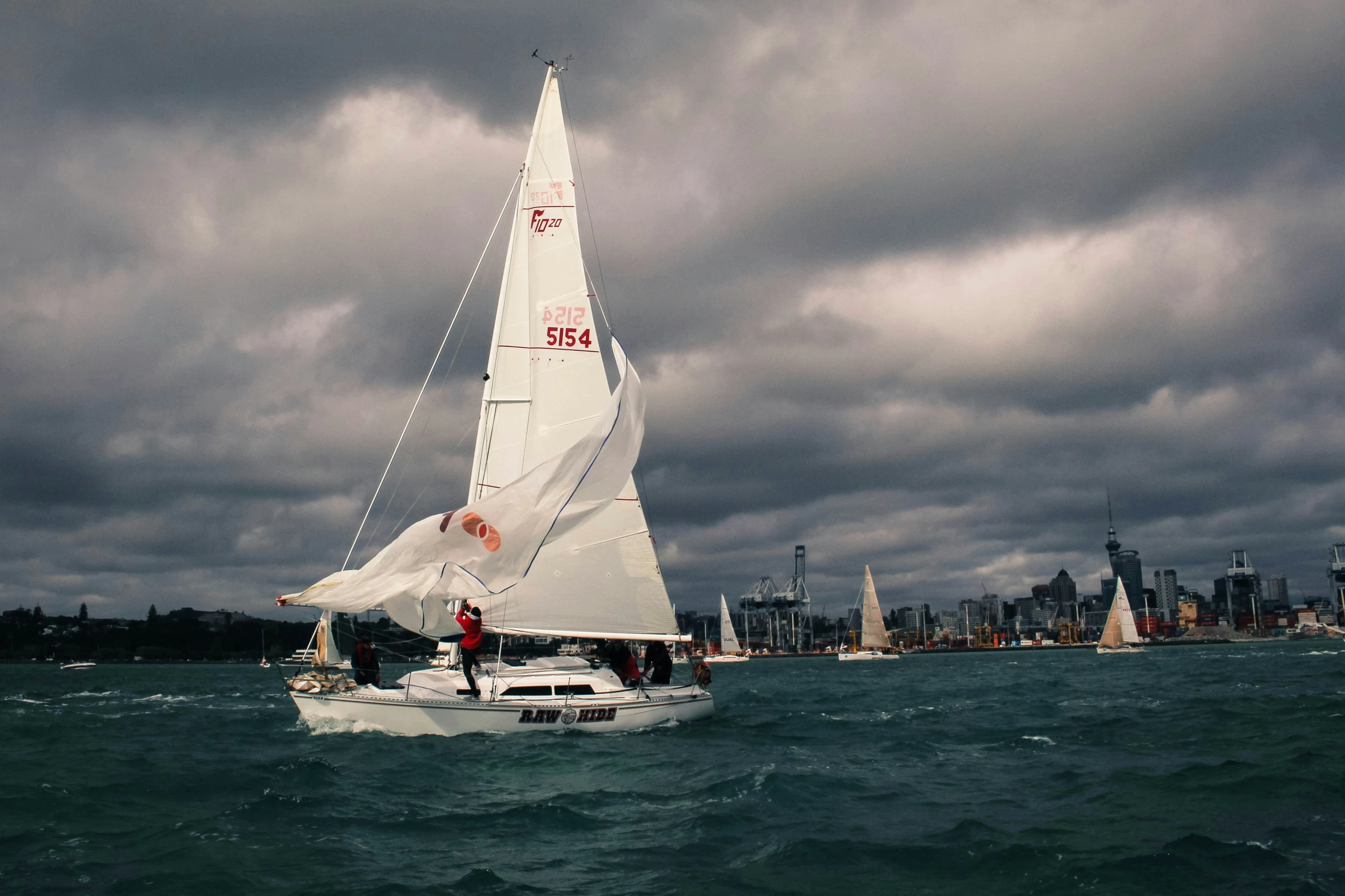 a white sail boat sailing in the ocean