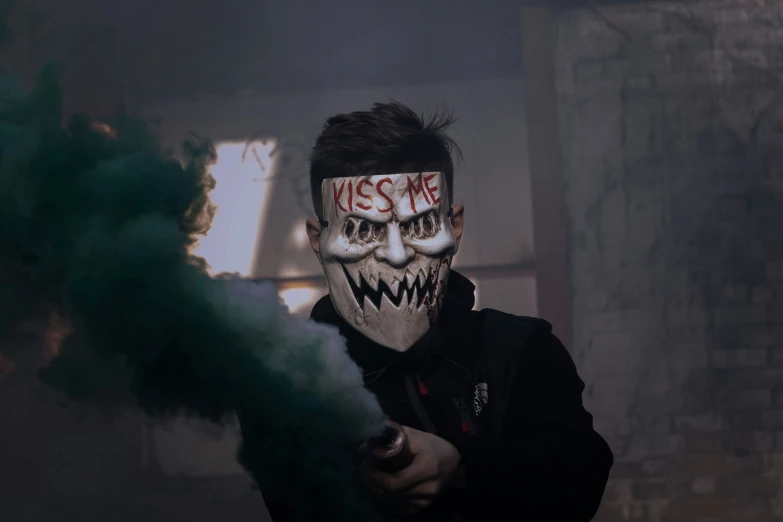 a person with painted face and black hoodie holding a smoke stick