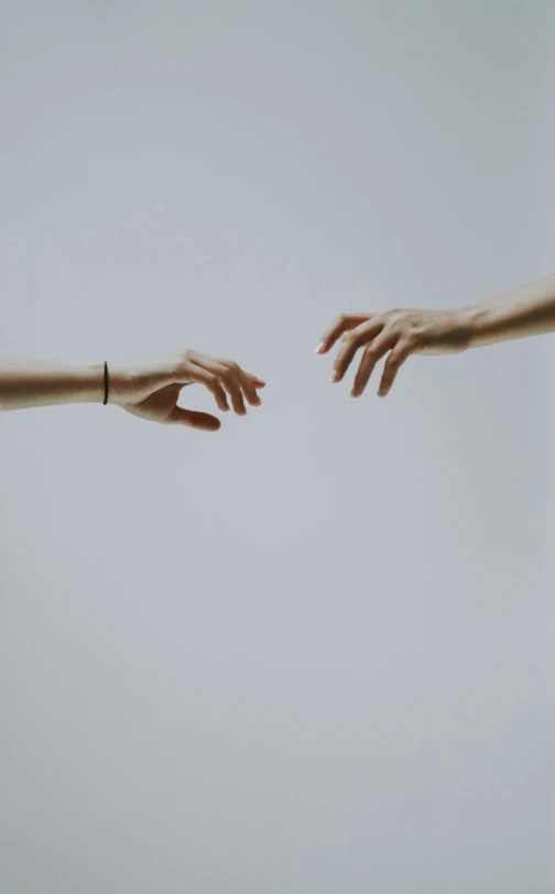 two hands reaching for each other towards the sky