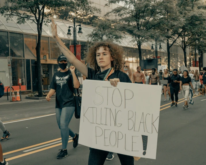 a woman on the street holding a sign in one hand and walking away