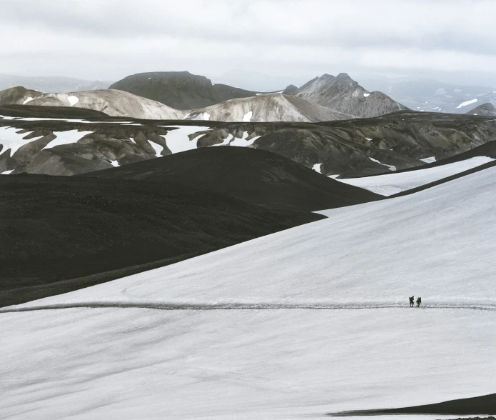 two people walk up to the top of a mountain