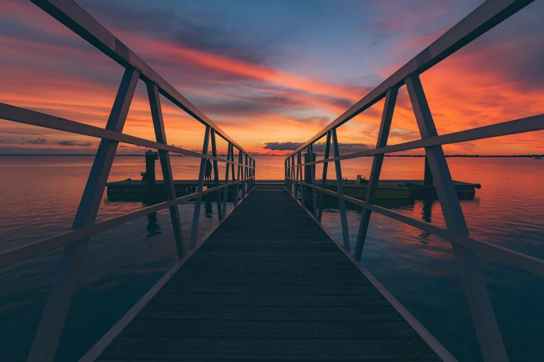 a dock at sunset with a colorful sky and clouds