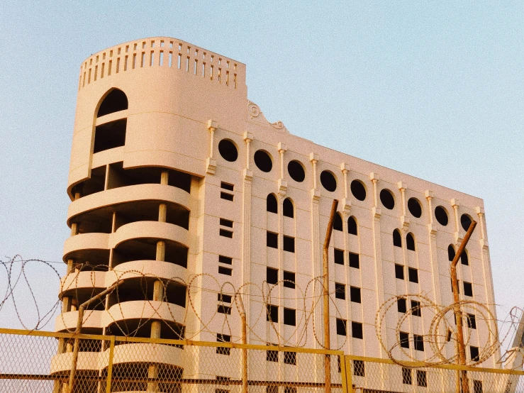 a white building with lots of windows sitting behind a fence