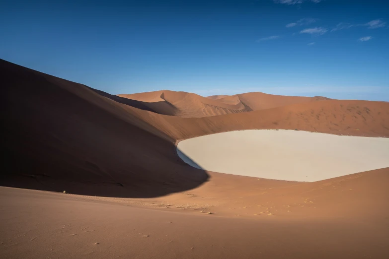 an expanse of sand with a pool and mountains in the distance