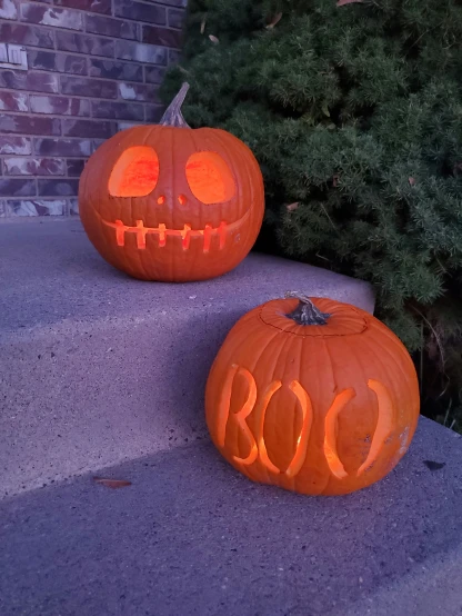 two pumpkins, one in the shape of boo and the other to be carved