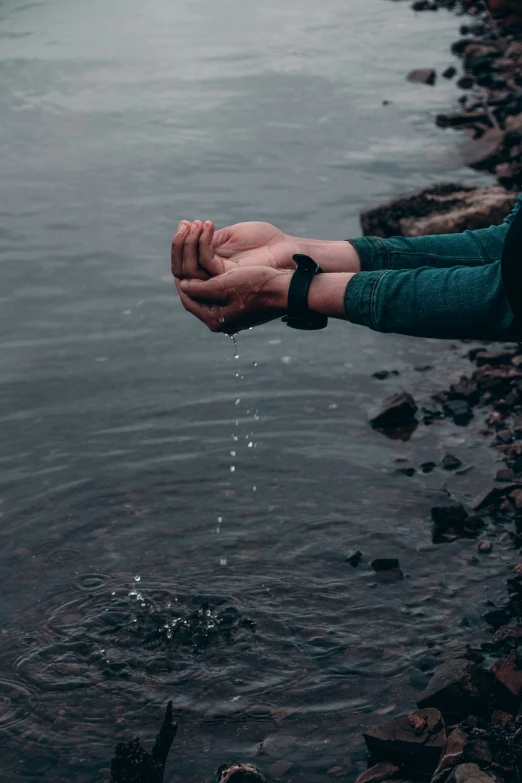 someone holding their hands out with water coming from the ground