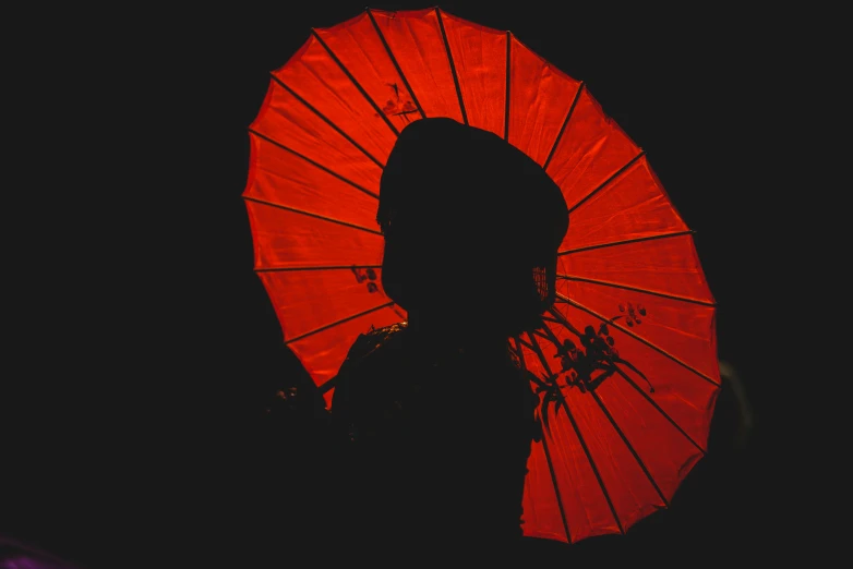 a person standing under a red umbrella