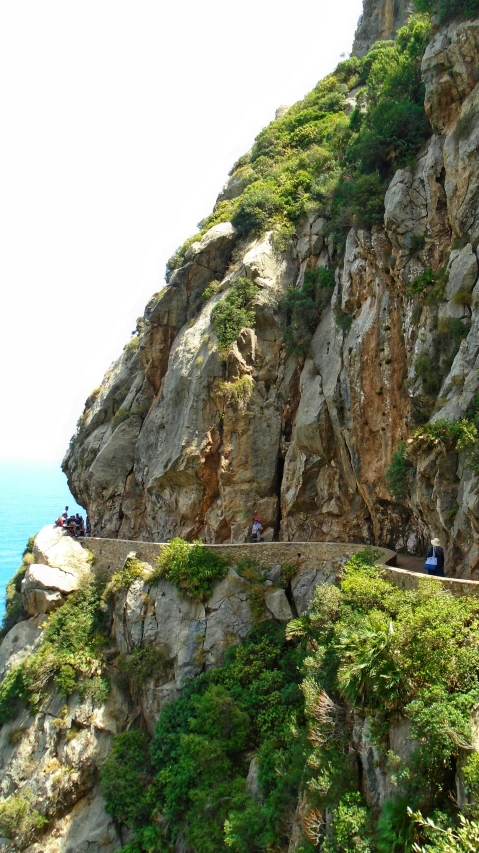 two people sitting on the edge of a large rock cliff