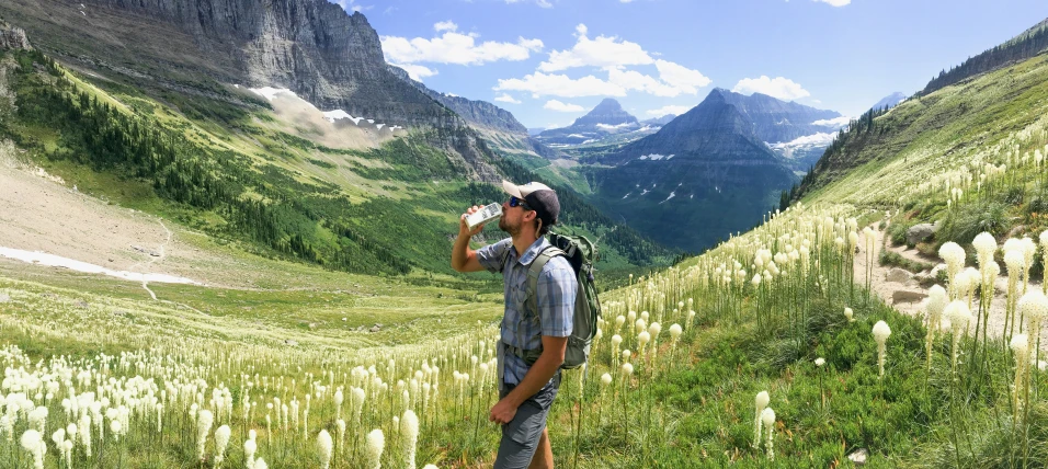 a man is drinking a cup on the side of a mountain