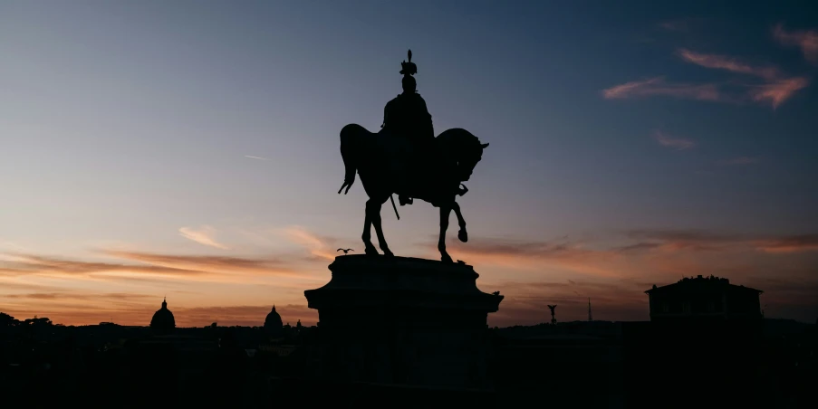 a statue with a horse on top and a city in the background