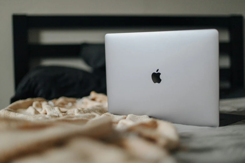 a macbook pro laptop sitting on a bed