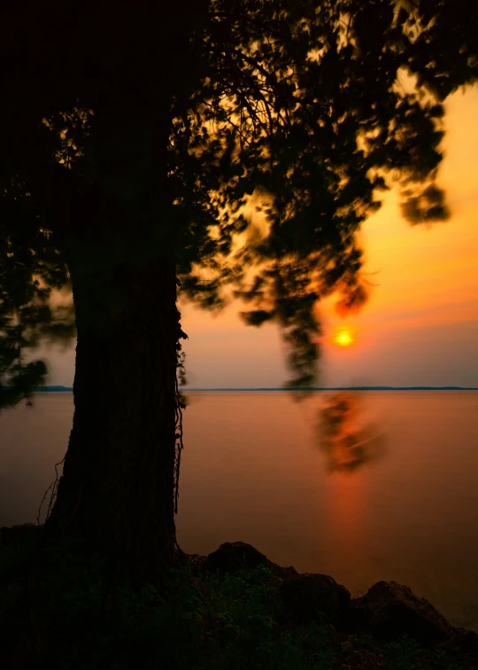 the sun sets in the sky over a body of water