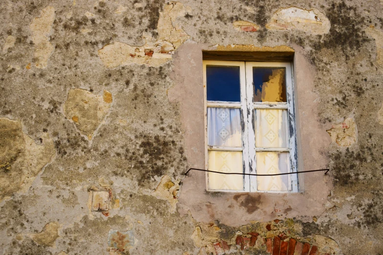 a dilapidated building with a closed window and bars in it