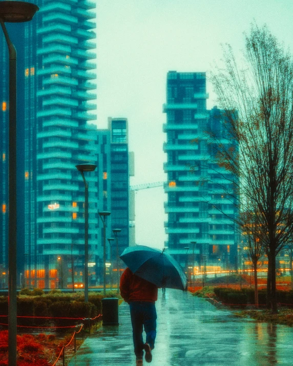 man walking down the street carrying an umbrella in the rain