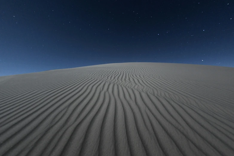 a large hill covered in sand under a sky filled with stars