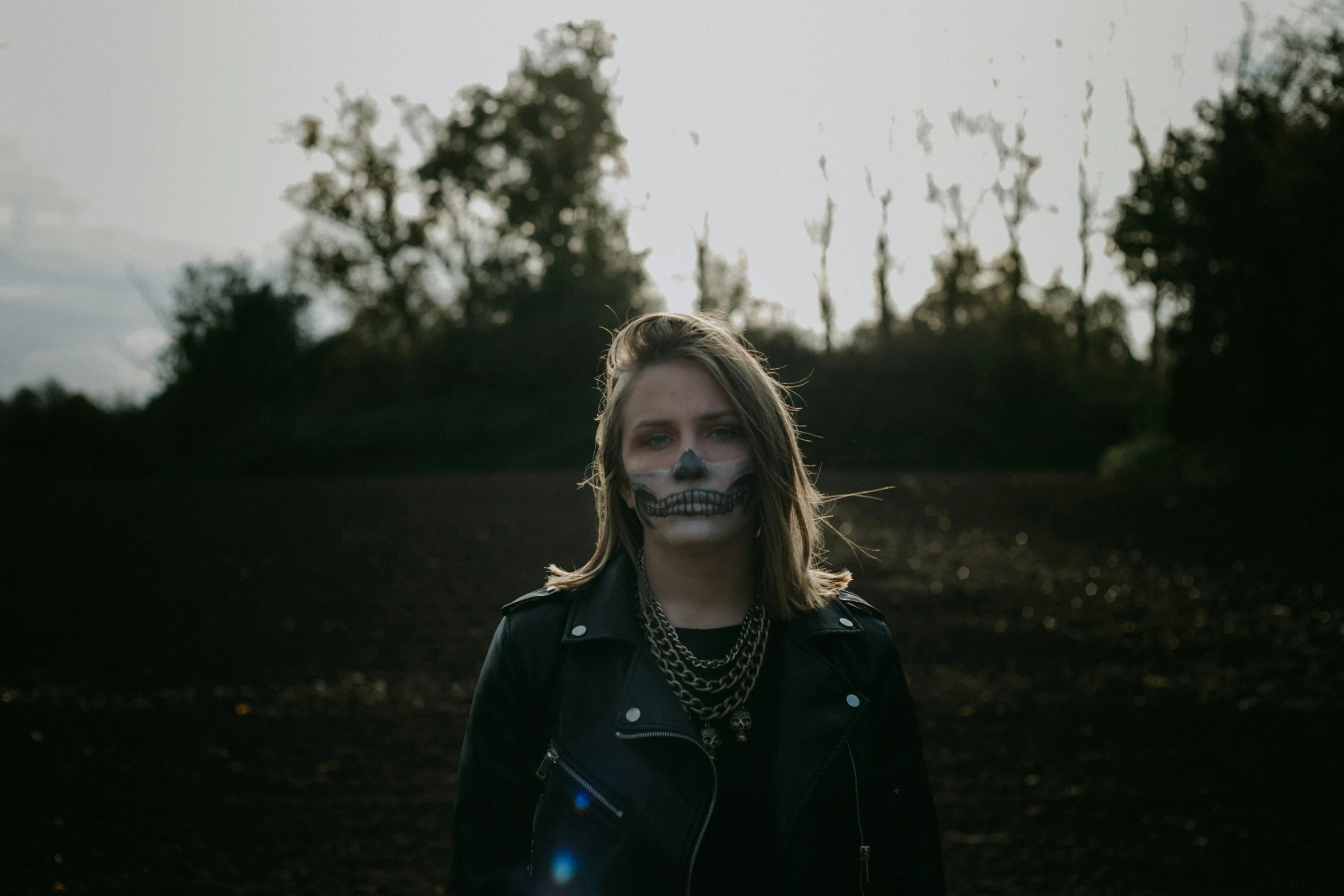 a man with face paint, black jacket, and chains in the evening