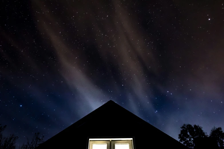 a dark sky with stars above a house at night