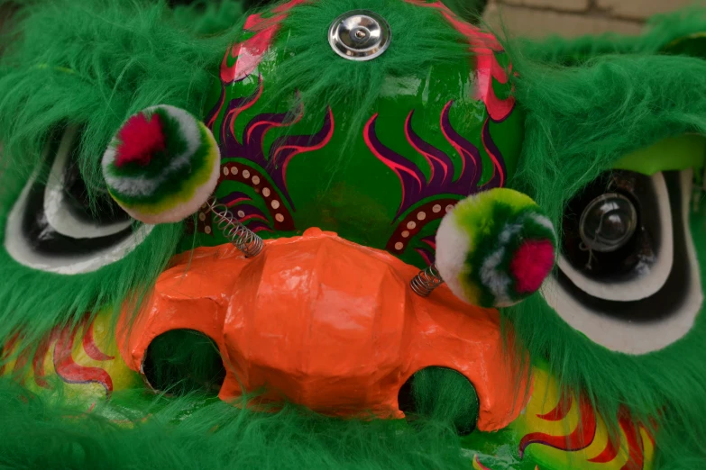 a green creature mask with an orange object on it