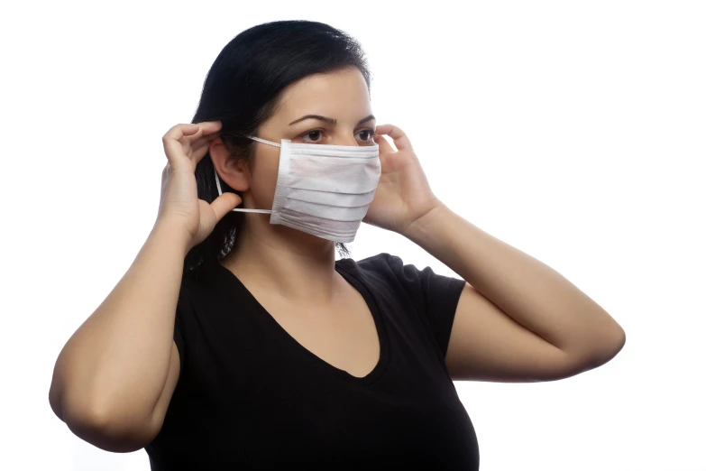 a young woman covering her face with a surgical mask