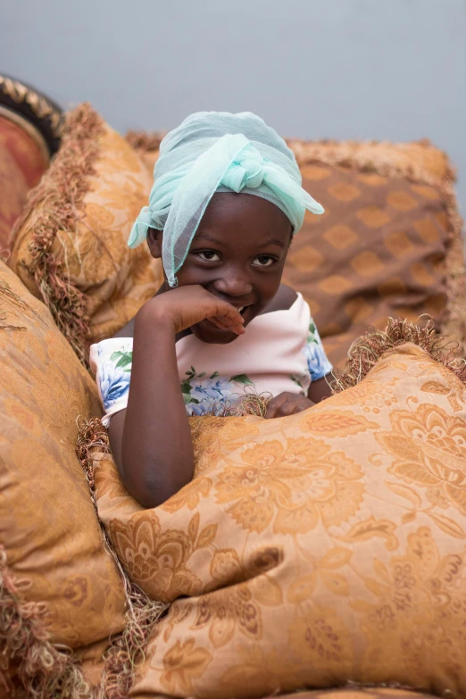 a little black girl sitting on top of a couch