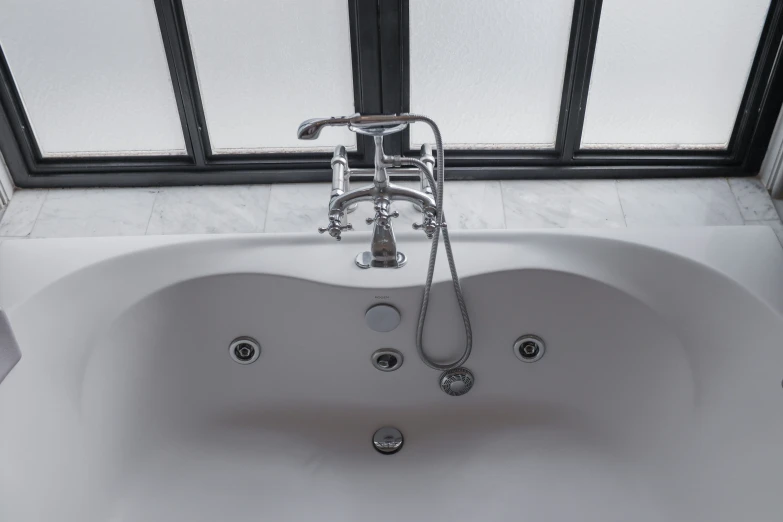 a bathtub filled with two faucets sitting in a bathroom