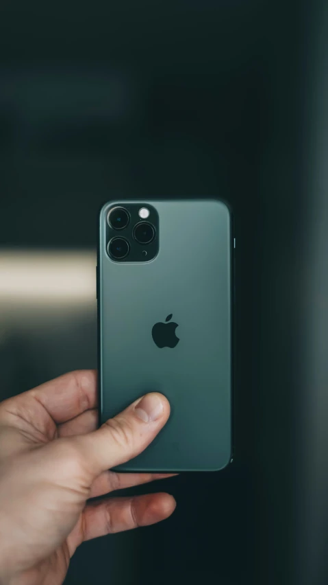 the iphone 11 is being held in front of a dark background