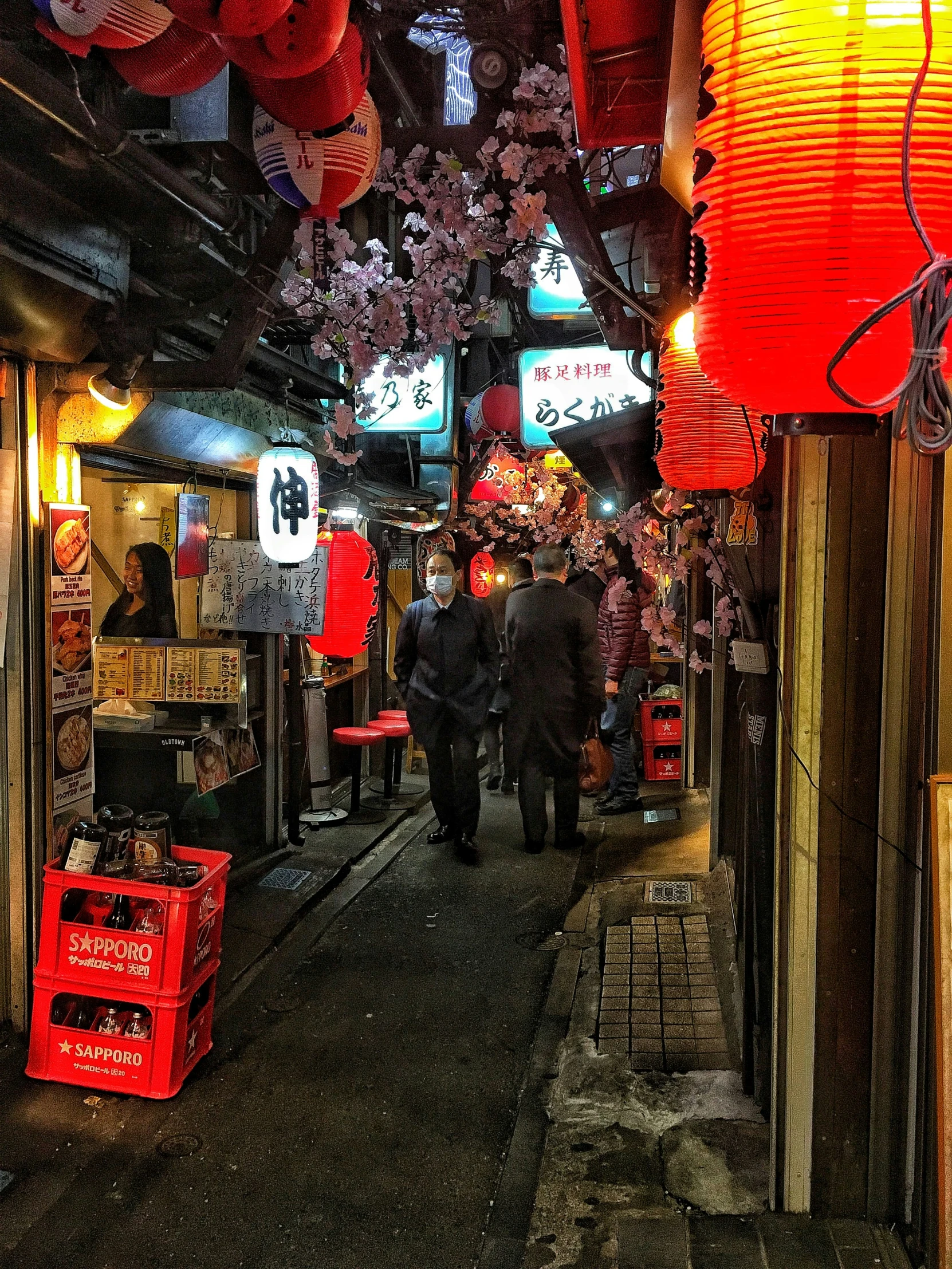 people walk down an alley way lined with lit stores