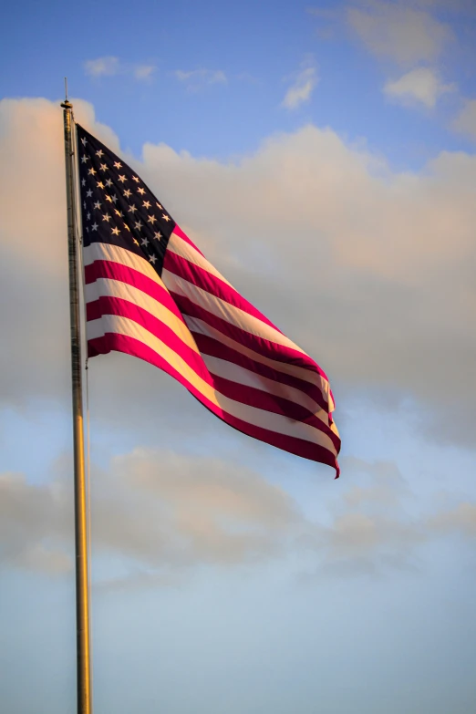 a very tall american flag with a beautiful blue sky in the background