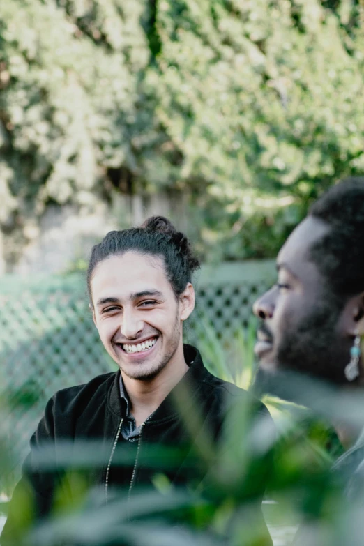 two smiling men sitting on a bench in a garden