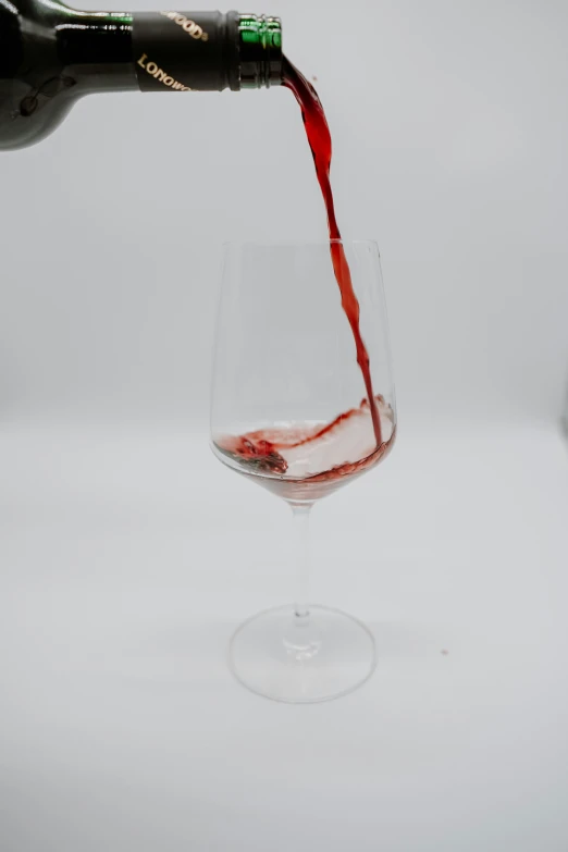 someone pouring a glass of wine into another wine glass