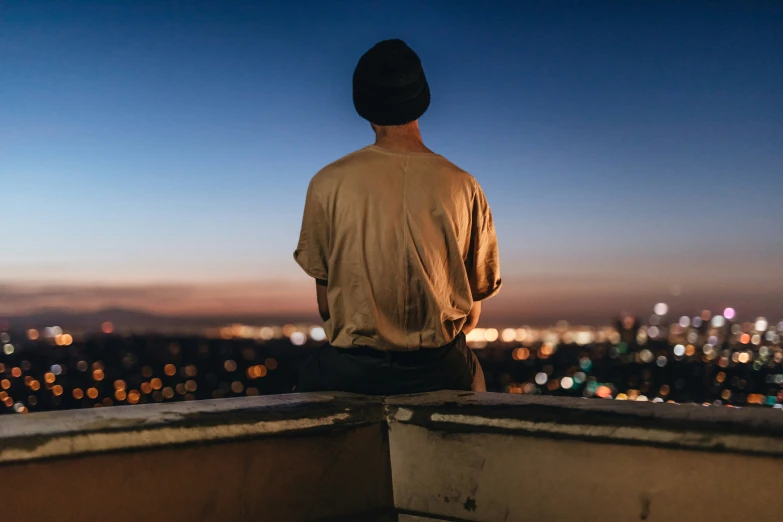 a man sits on the top of a tower while watching the city