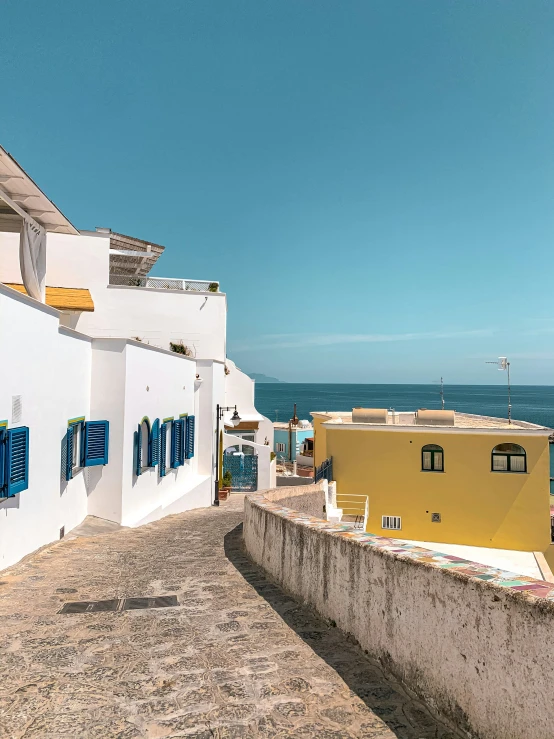 an alley way with blue shuttered windows near the ocean