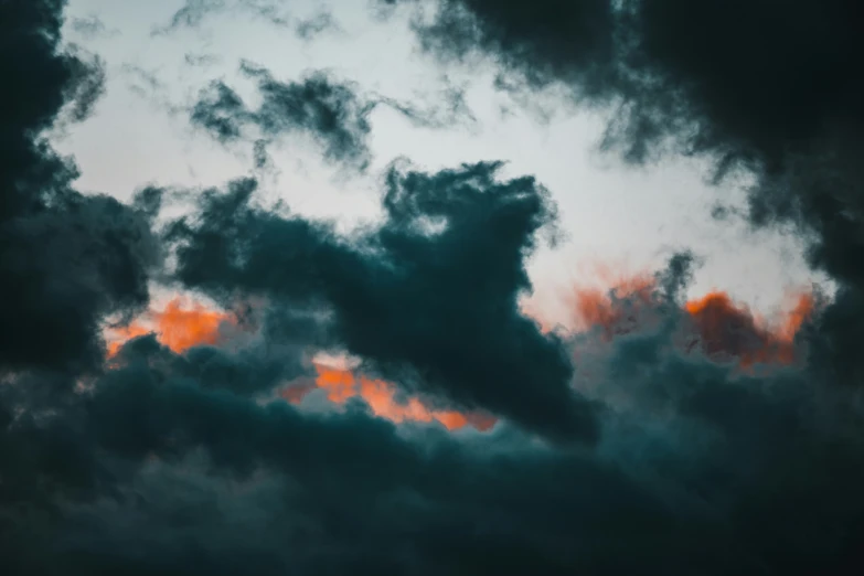a plane flies through a cloudy sky, with dark clouds