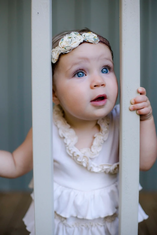 a cute little baby looking out through the bars