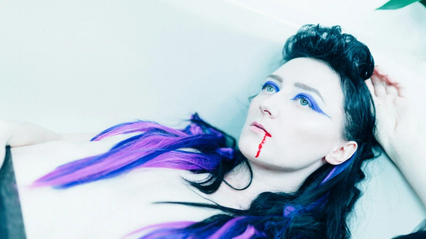 woman laying down with purple hair and  on her face